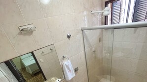 Un baño moderno con ducha envuelta en vidrio, un lavamanos con espejo y un inodoro.