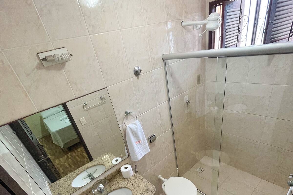 Ein modernes Badezimmer mit einer gläsernen Duschkabine, einem Waschbecken inklusive Spiegel und einer Toilette.
