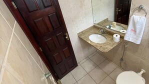 Un baño con puerta de madera, un lavabo, un inodoro y un espejo.