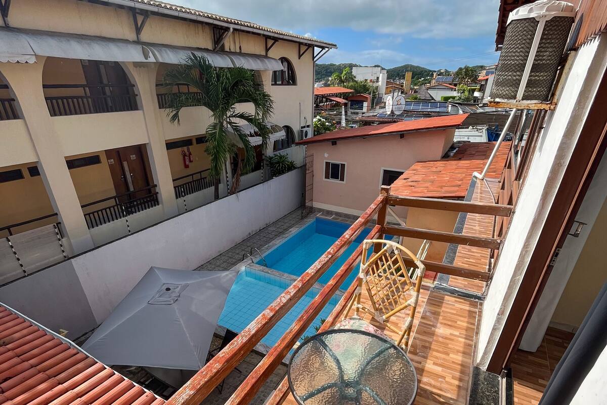 Eine Dachterrasse mit Pool, Holzdeck und einem Glastisch mit Korbstuhl.