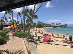 A beach with palm trees, umbrellas, and people. - The Napili Bay, Steps to Sand, Studio, King bed, Remodeled in June of 2023 (Lahaina)