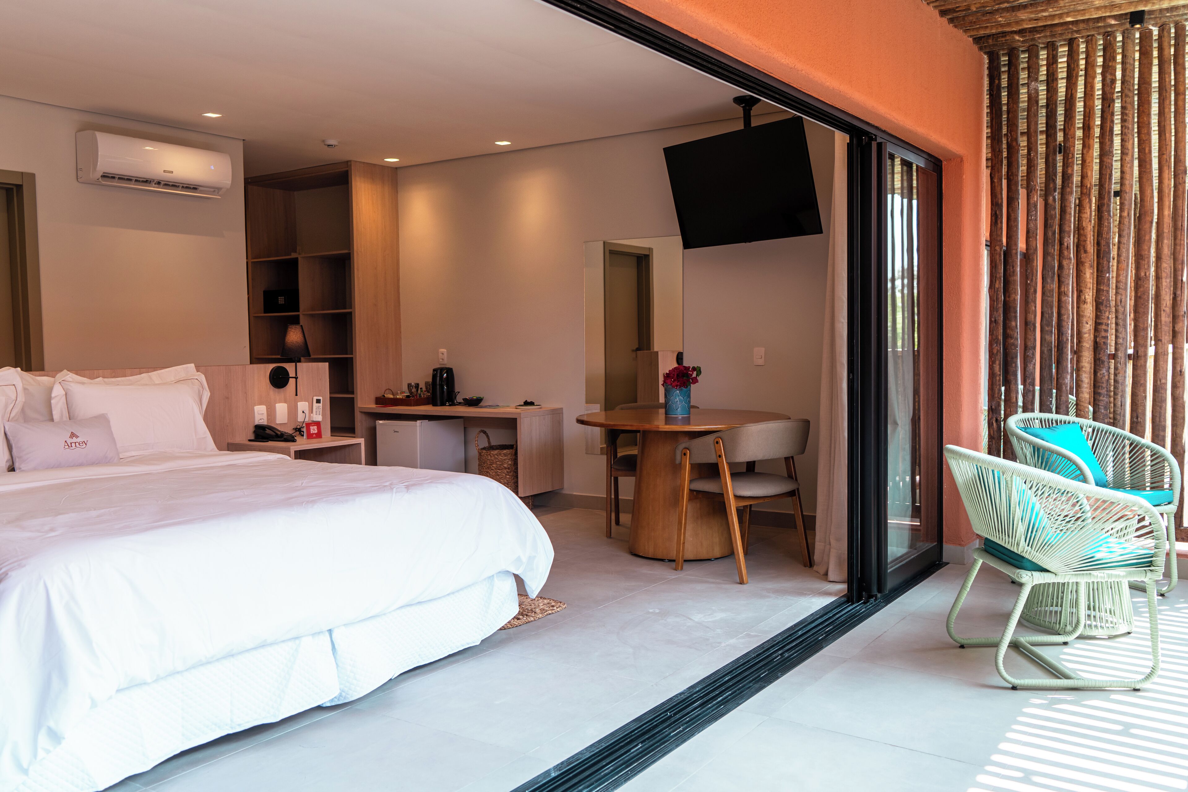 A modern hotel room with a bed, desk, chair, and a TV mounted on the wall.