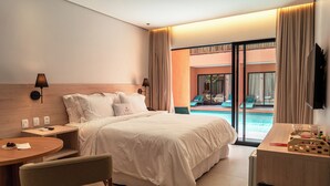 A hotel room with a large bed, a desk with a chair, a small table, a TV, and a view of a pool.