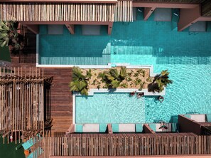 An aerial view of a pool area with wooden deck seating and palm plants. - Arrey Boutique Hotel (Cajueiro da Praia)