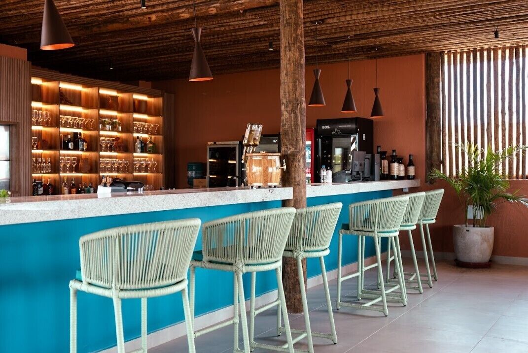 A bar area with a wooden ceiling, bar stools, and a counter with bottles and glasses.