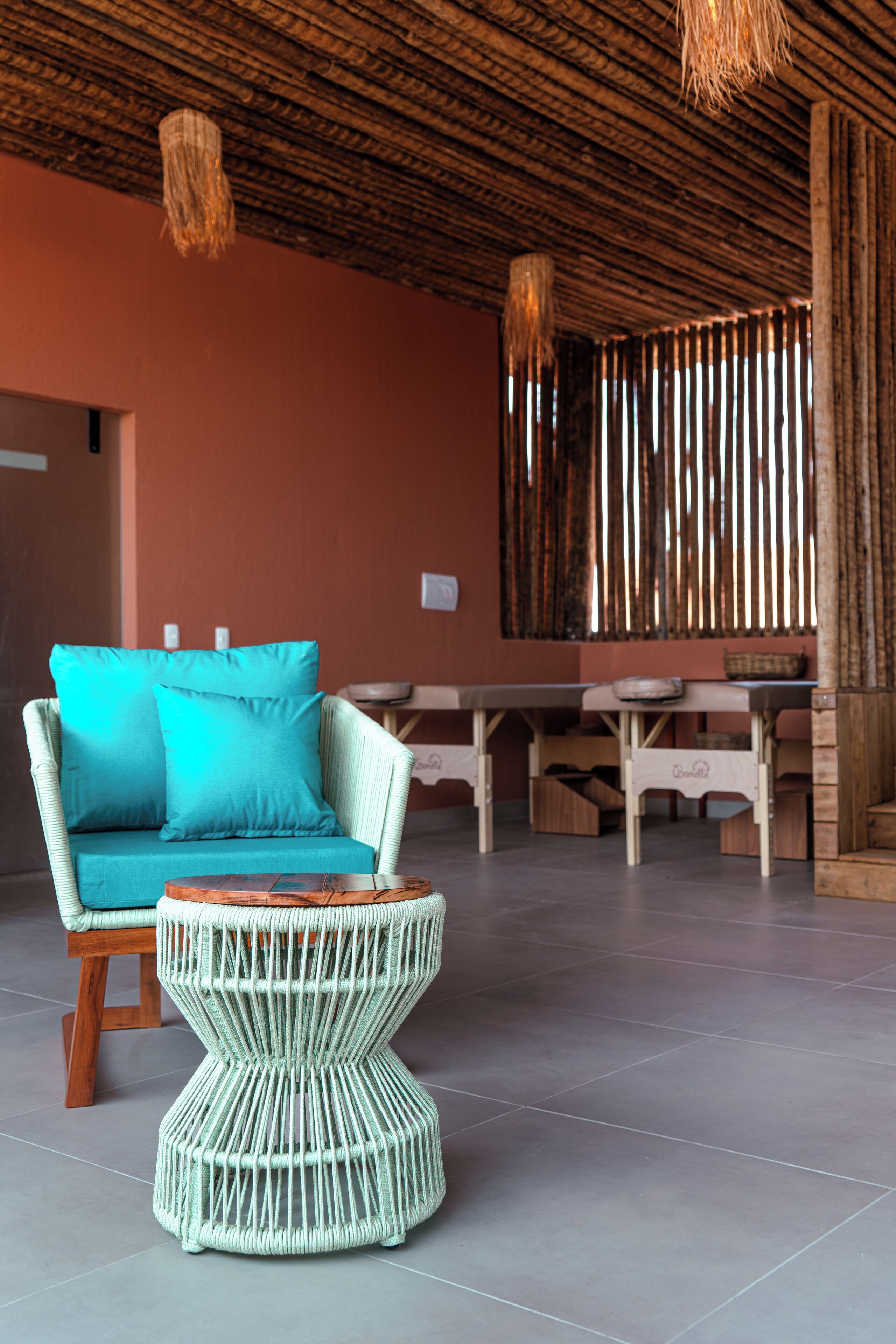 A room with a woven sofa, a round wicker coffee table, and a wooden dining table.