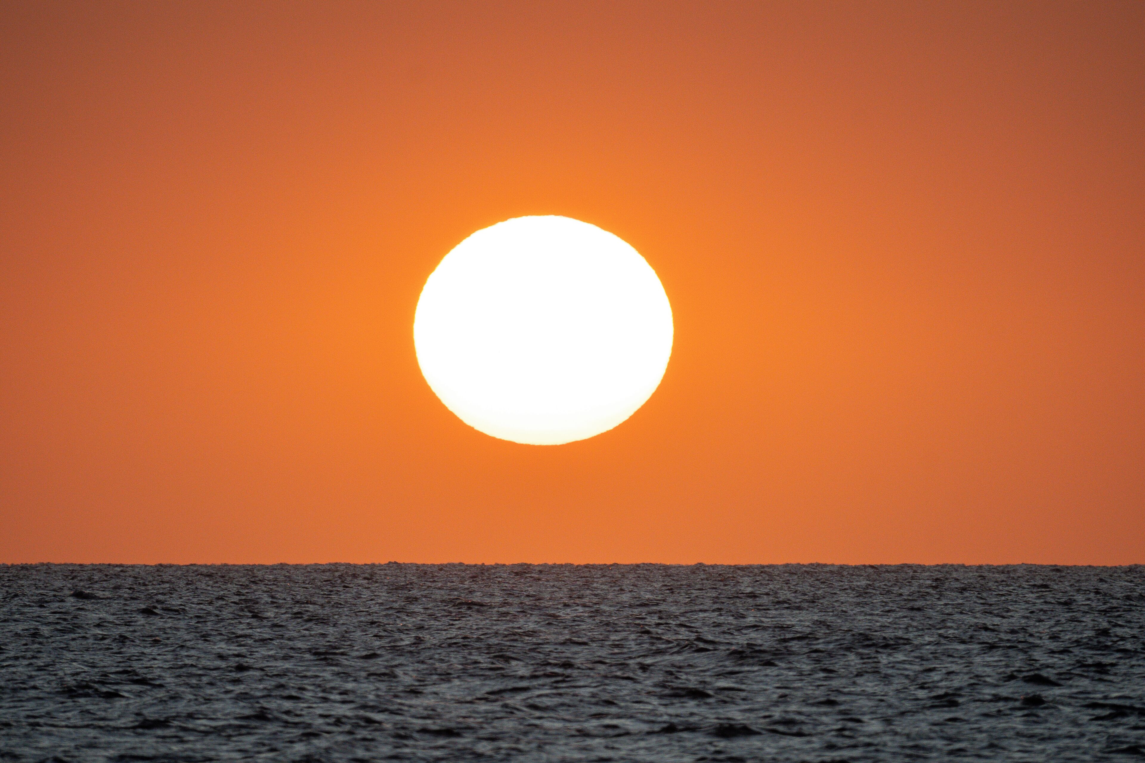 Solnedgang over havet med en klar himmel.