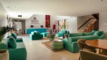 Un moderno vestíbulo de hotel con sofás color turquesa, un mostrador de recepción y una escalera.