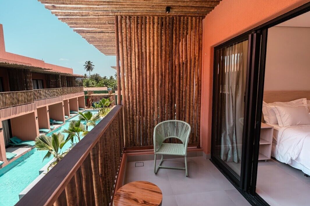 A balcony with a view of a pool, a chair, and a bed.