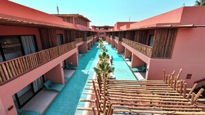 A hotel with a central pool, wooden railings, and a clear sky.