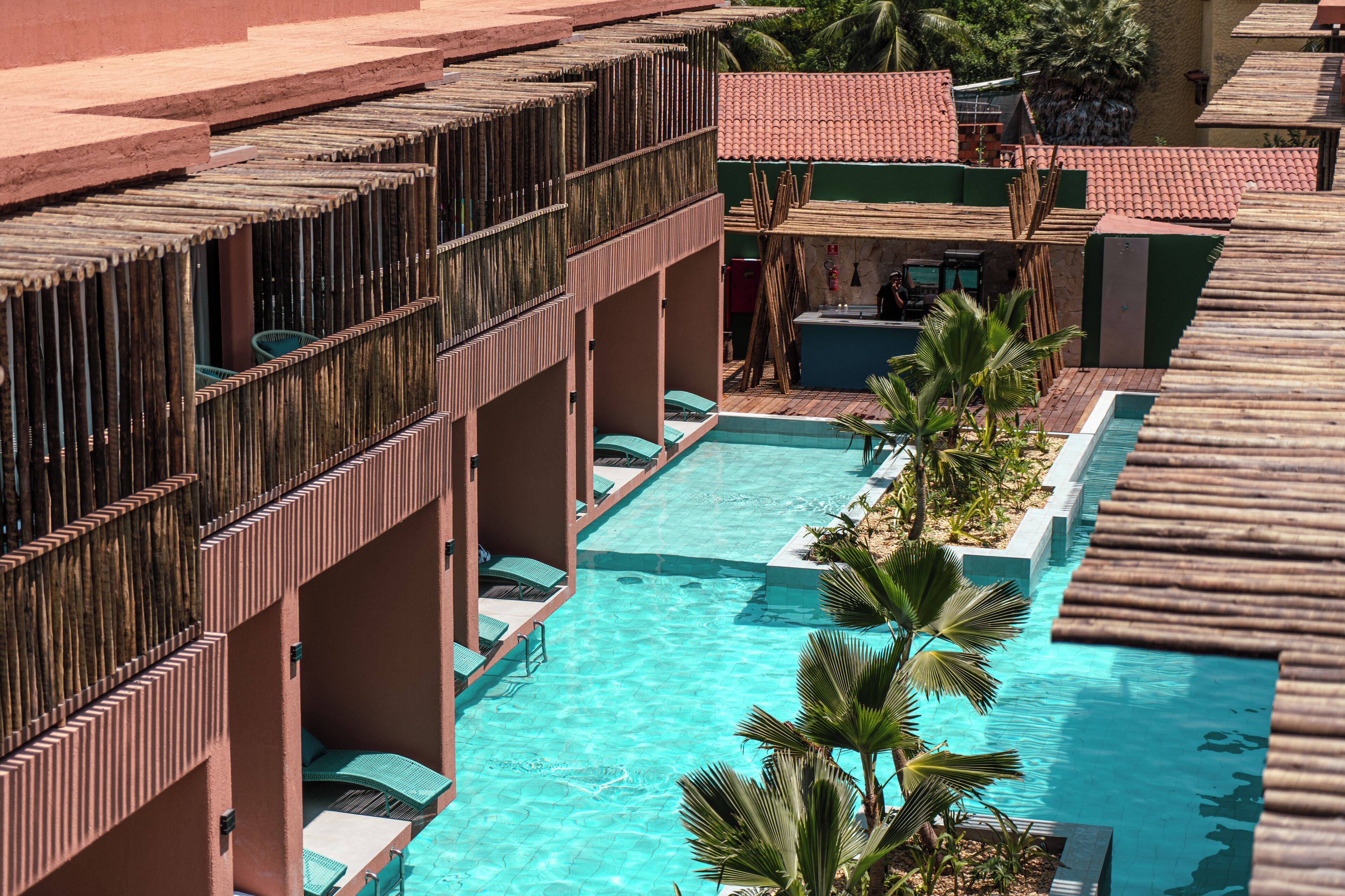 Un hotel con piscina, varios balcones y palmeras.