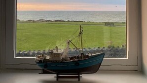 A model ship on a windowsill with a view of a grassy field and the sea. - The Lifeboat House, Skerries Harbour (Skerries)