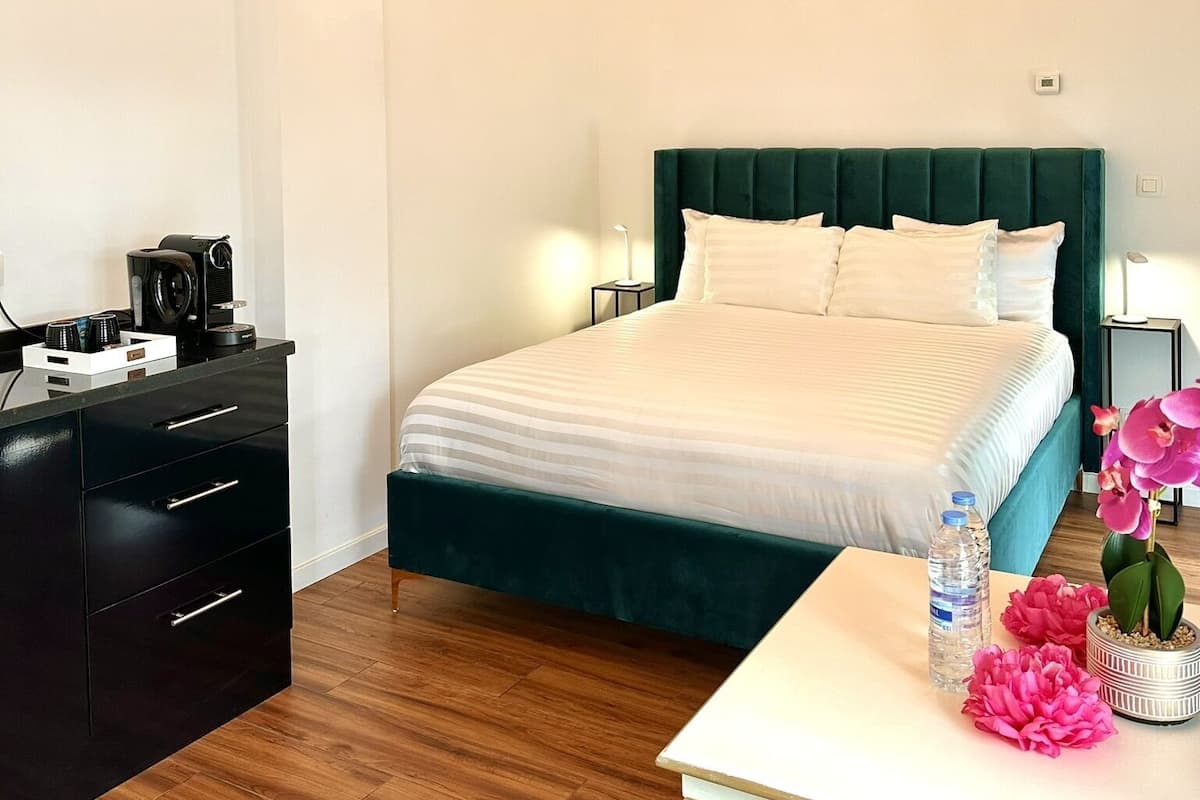 A hotel room with a bed, a desk, a dresser, and a chandelier.