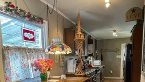 A kitchen with a wooden island, bar stools, a hanging light fixture, and a 'LOVE' sign on the wall. - Watkins Glen Village Home, Walk to Gorge & Downtown! (Watkins Glen)
