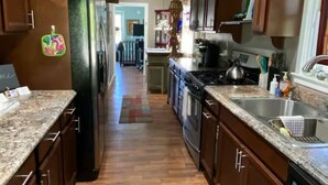 A kitchen with wooden cabinets, a refrigerator, a stove, and a sink. - Watkins Glen Village Home, Walk to Gorge & Downtown! (Watkins Glen)