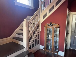 Stairs lead to an upper level, adjacent to a display cabinet showcasing various items.