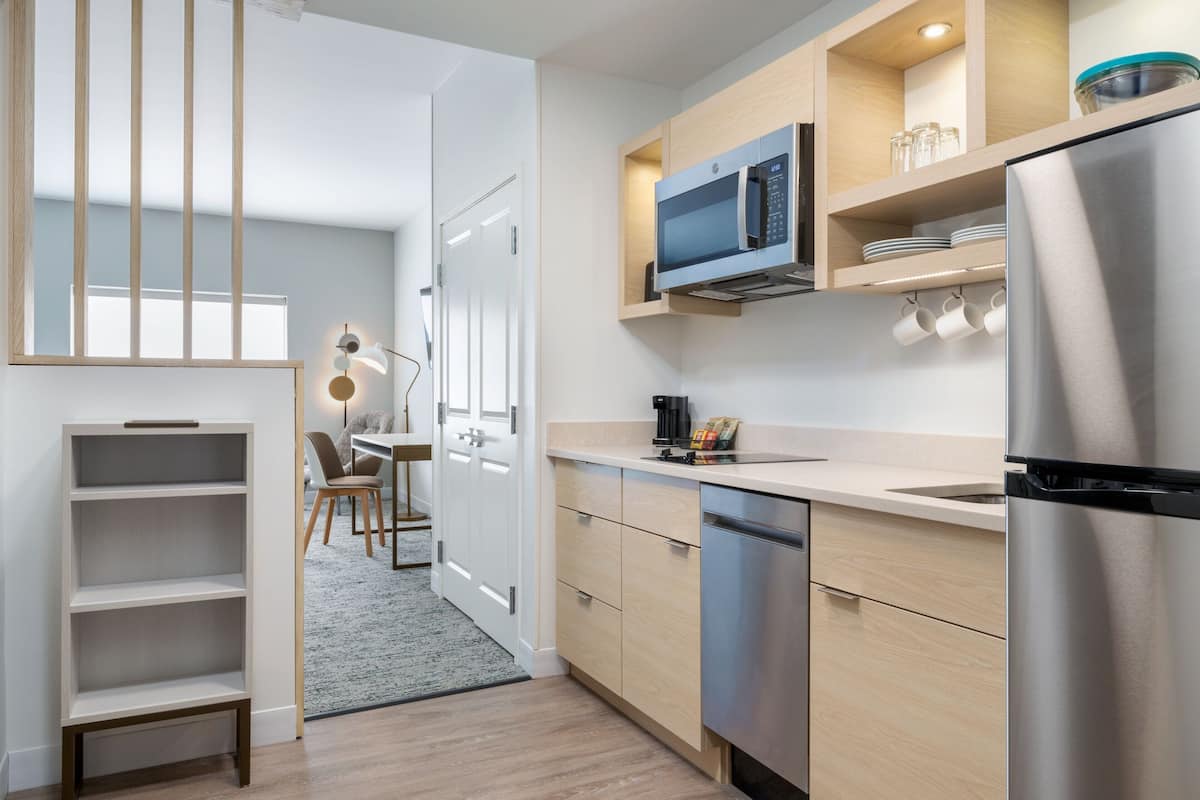 Eine moderne Küche mit eingebauter Mikrowelle, einem Edelstahl-Kühlschrank und Holzschränken.