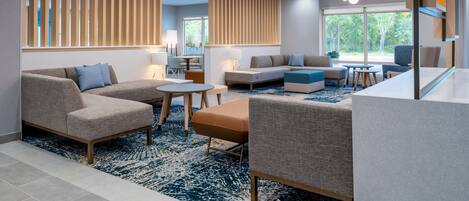 A modern living room with a sectional sofa, a round coffee table, and a blue patterned rug.