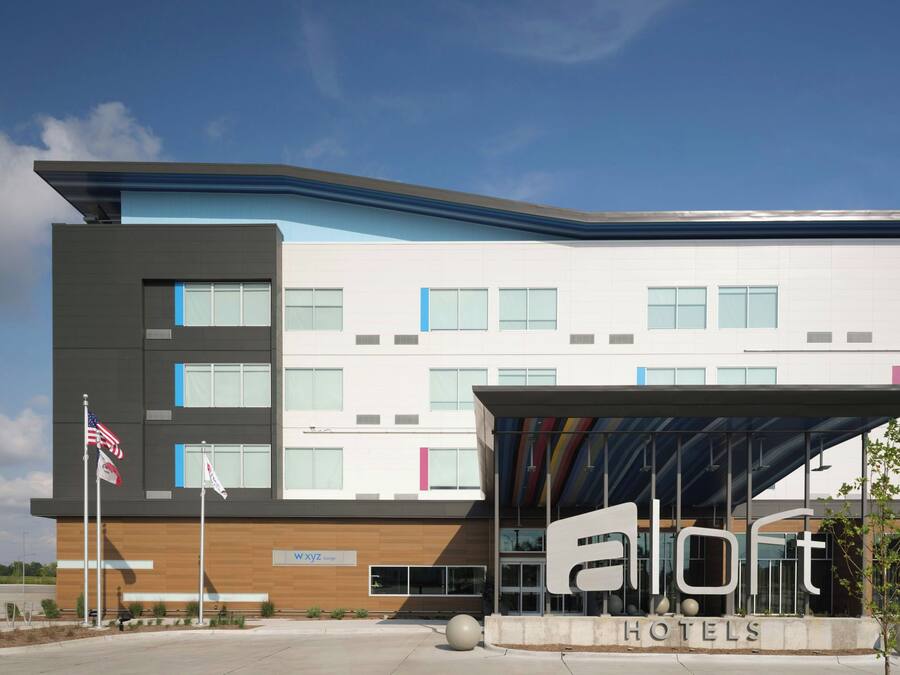 A modern hotel building with a flat roof, multiple windows, and a covered entrance area.