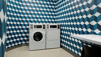 A laundry room with a patterned wall, a washing machine, and a table.