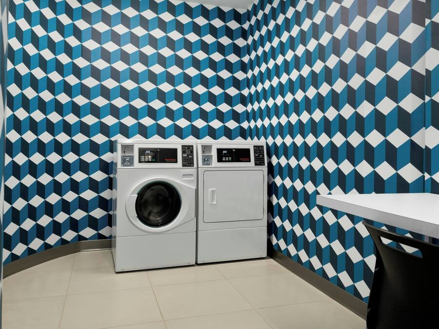 A laundry room with a patterned wall, a washing machine, and a table.