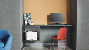 A modern office desk with a computer monitor, a printer, and a chair.