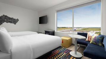 Habitación de hotel moderna con una cama grande, una mesita, un sofá y vistas al campo.