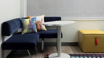 Een zithoek met een blauwe bank, een klein rond tafeltje en een kleurrijk vloerkleed.
