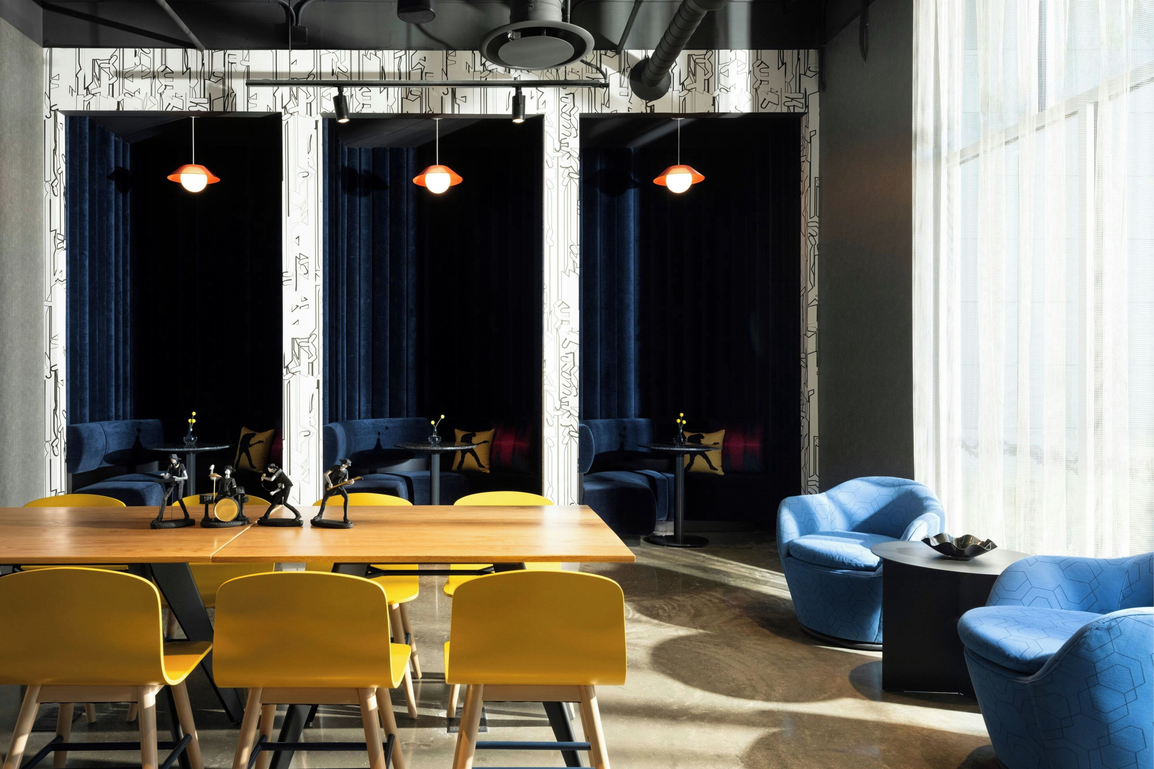 A conference room with a wooden table, yellow chairs, blue sofas, and a patterned wall.
