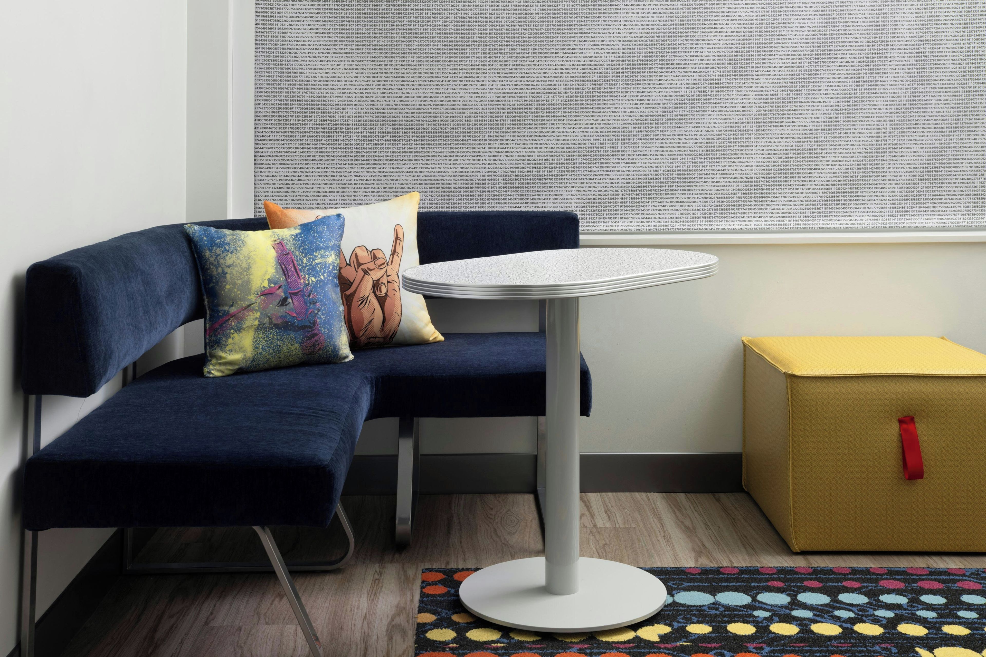 Un coin salon avec un canapé bleu, une petite table ronde et un tapis coloré.