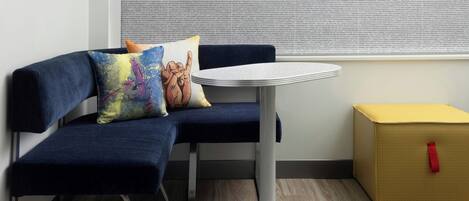 Un coin salon avec un canapé bleu, une petite table ronde et un tapis coloré.