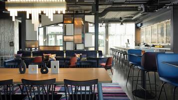 Een moderne kantoorruimte met een lange tafel, stoelen, een bank en een bar.