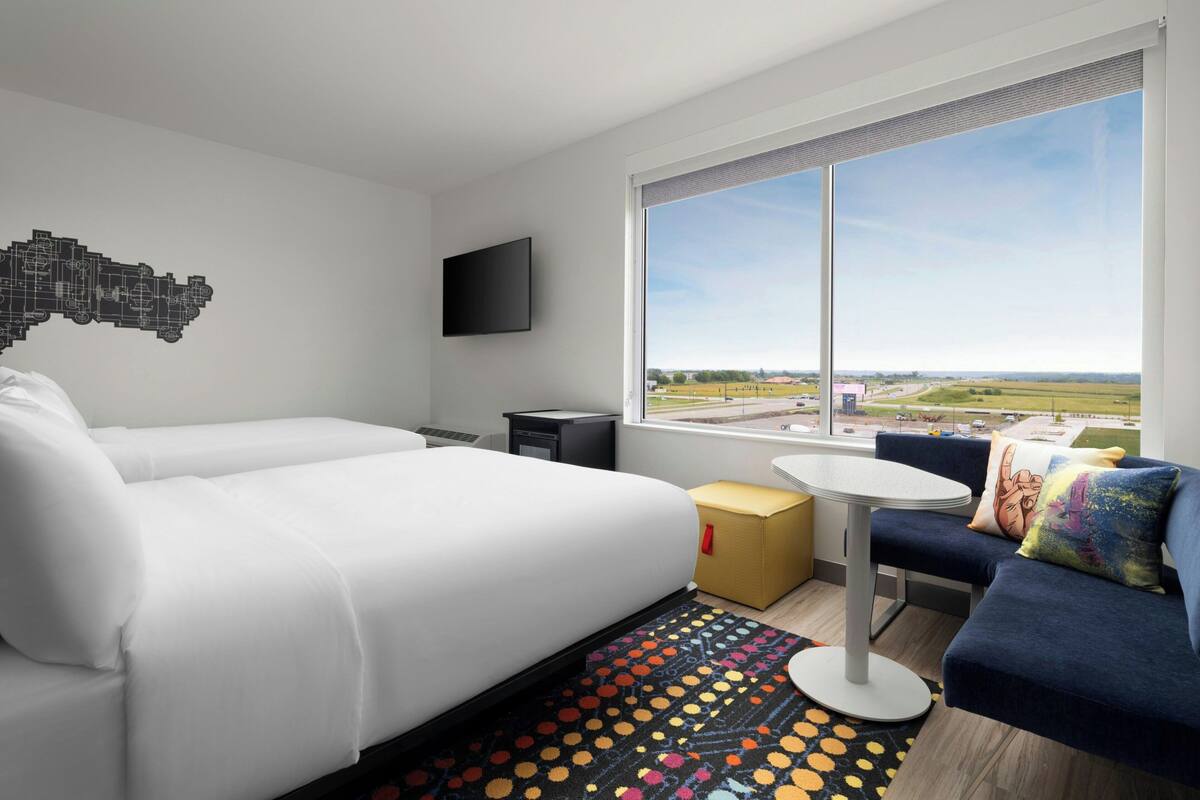 A modern hotel room with a large bed, a sofa, a small table, and a TV.