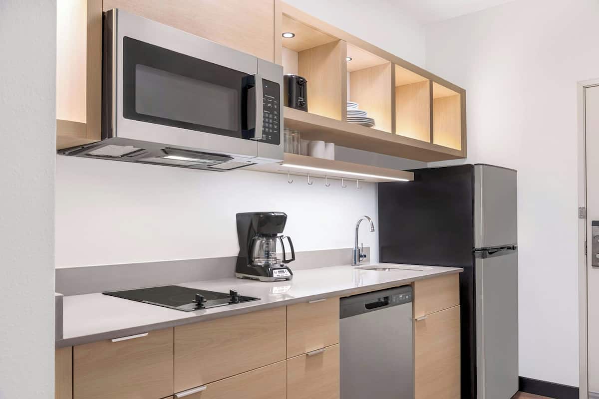 A modern kitchen with a built-in microwave, coffee maker, and dishwasher.