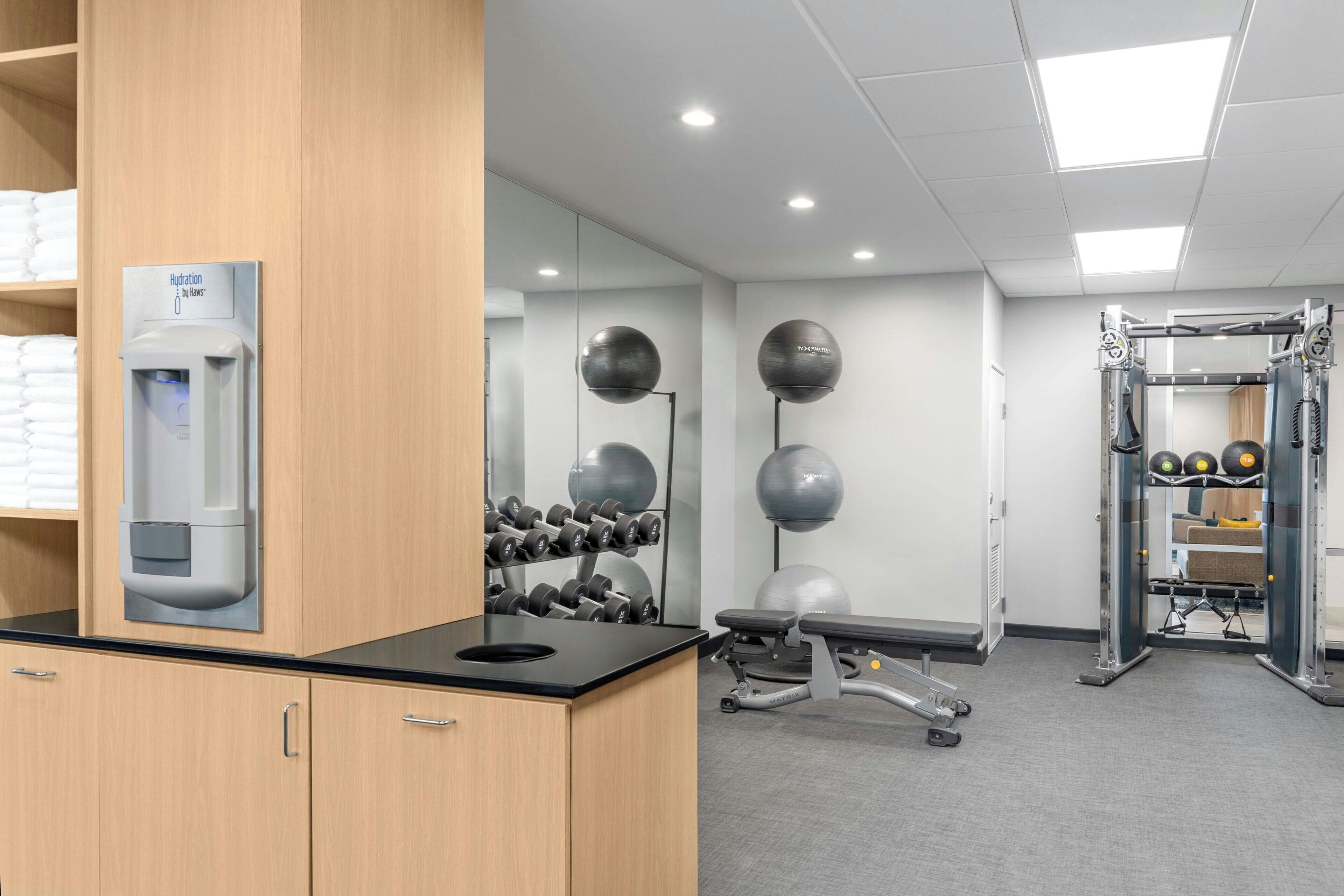 Un gimnasio con equipamiento de ejercicio, una estación de hidratación y un espejo.