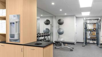 Un gimnasio con equipamiento de ejercicio, una estación de hidratación y un espejo.