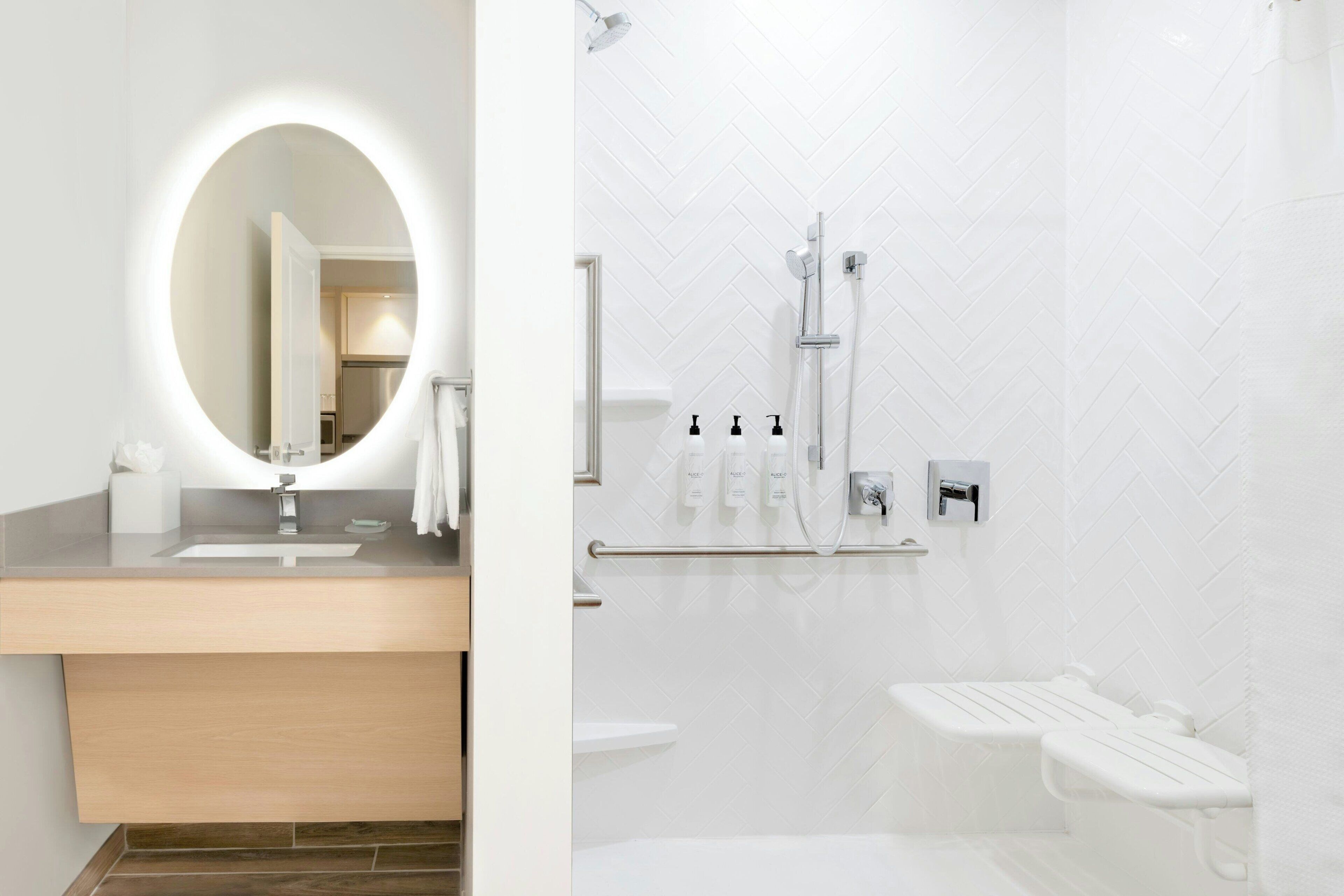 Un baño moderno con un espejo redondo, un lavabo y una zona de ducha.
