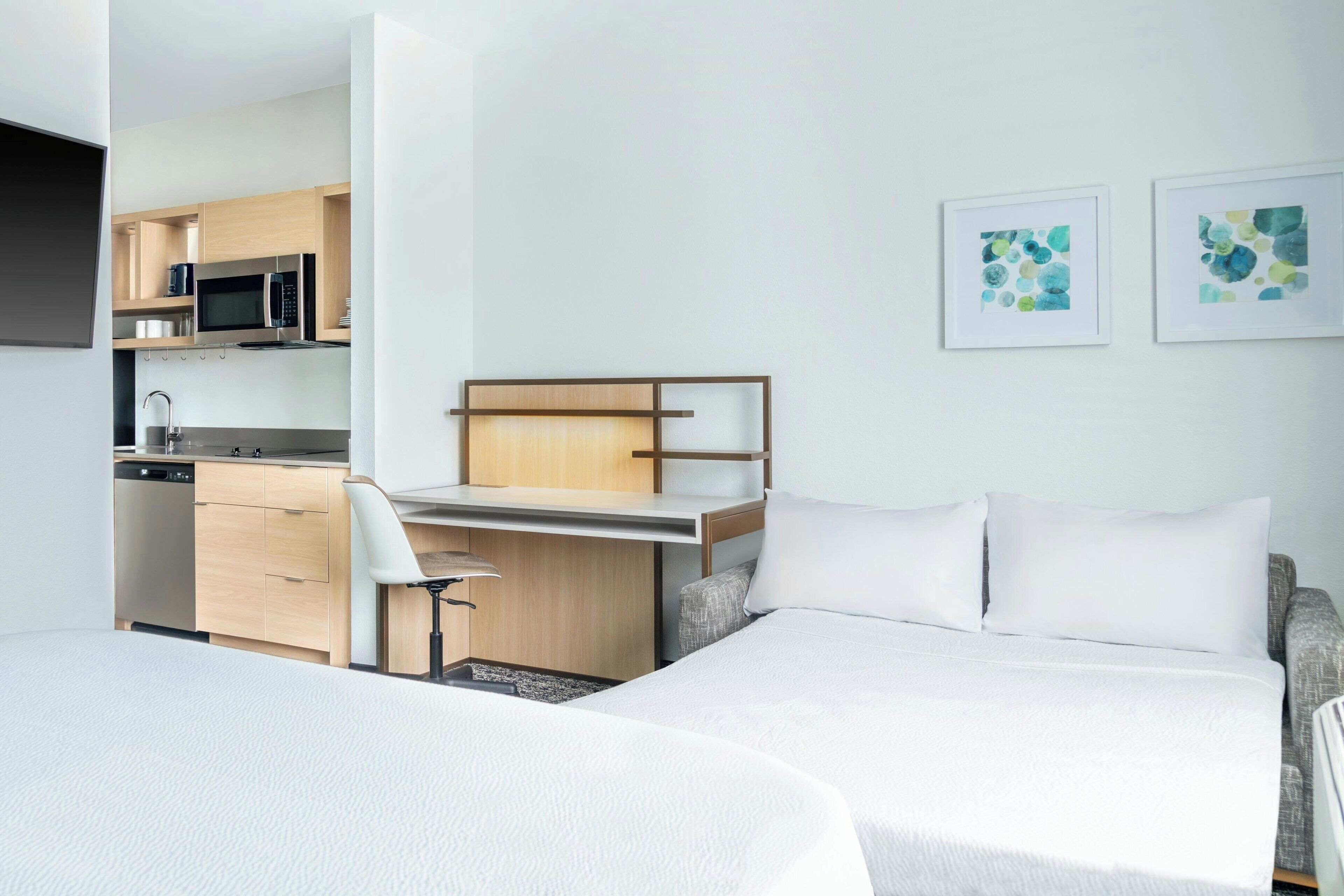 Una habitación de hotel moderna con cama, escritorio y kitchenette.