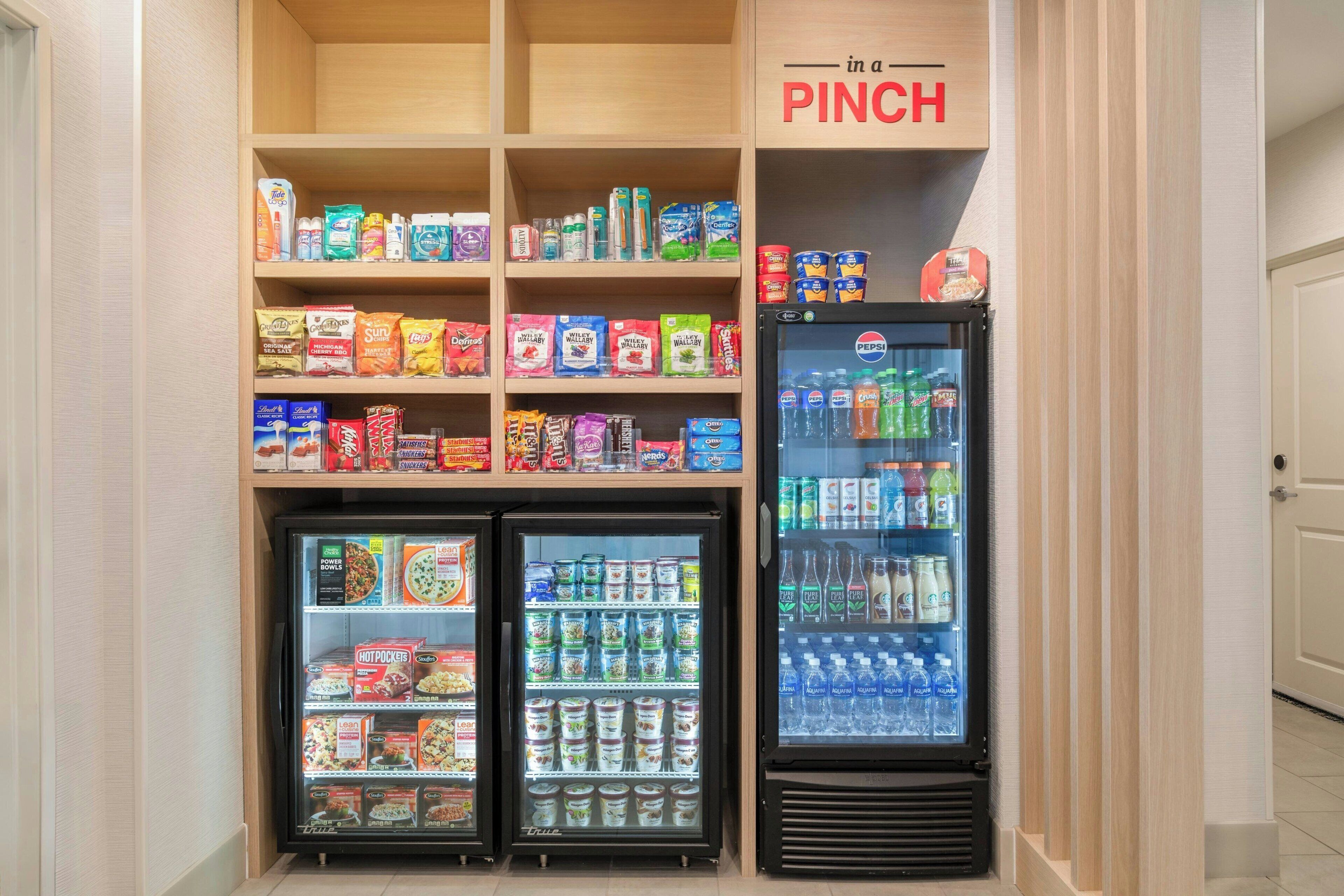 Mostrador de aperitivos y bebidas en el vestíbulo de un hotel con un cartel que dice 'PINCH'.