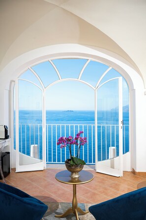 A balcony with a view of the sea, a round table with a vase of flowers, and blue chairs. - Villa Santa Chiara Positano (Positano)