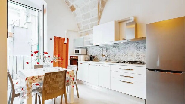 Een moderne keuken met witte kastjes, een roestvrijstalen koelkast en een betegelde achterwand.