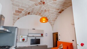 Een moderne keuken met een gasfornuis, witte kasten en een flatscreen televisie.