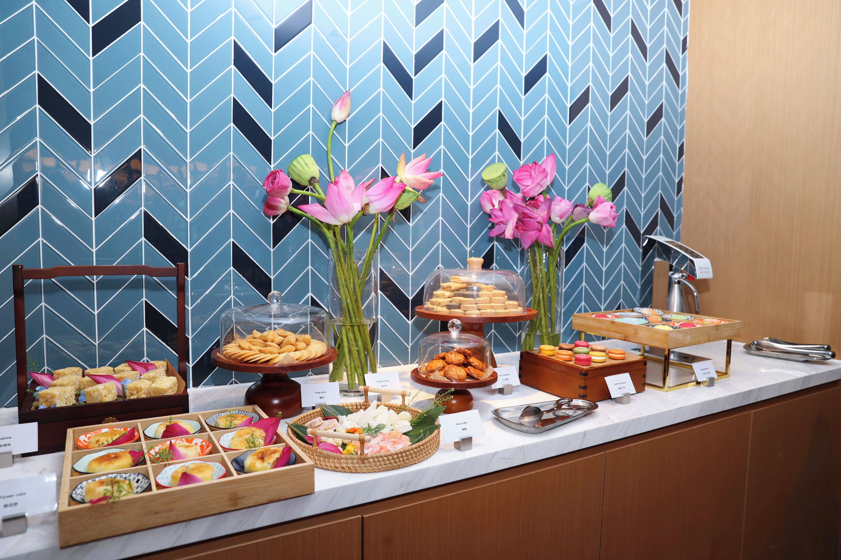 A buffet with various food items and decorative flowers.