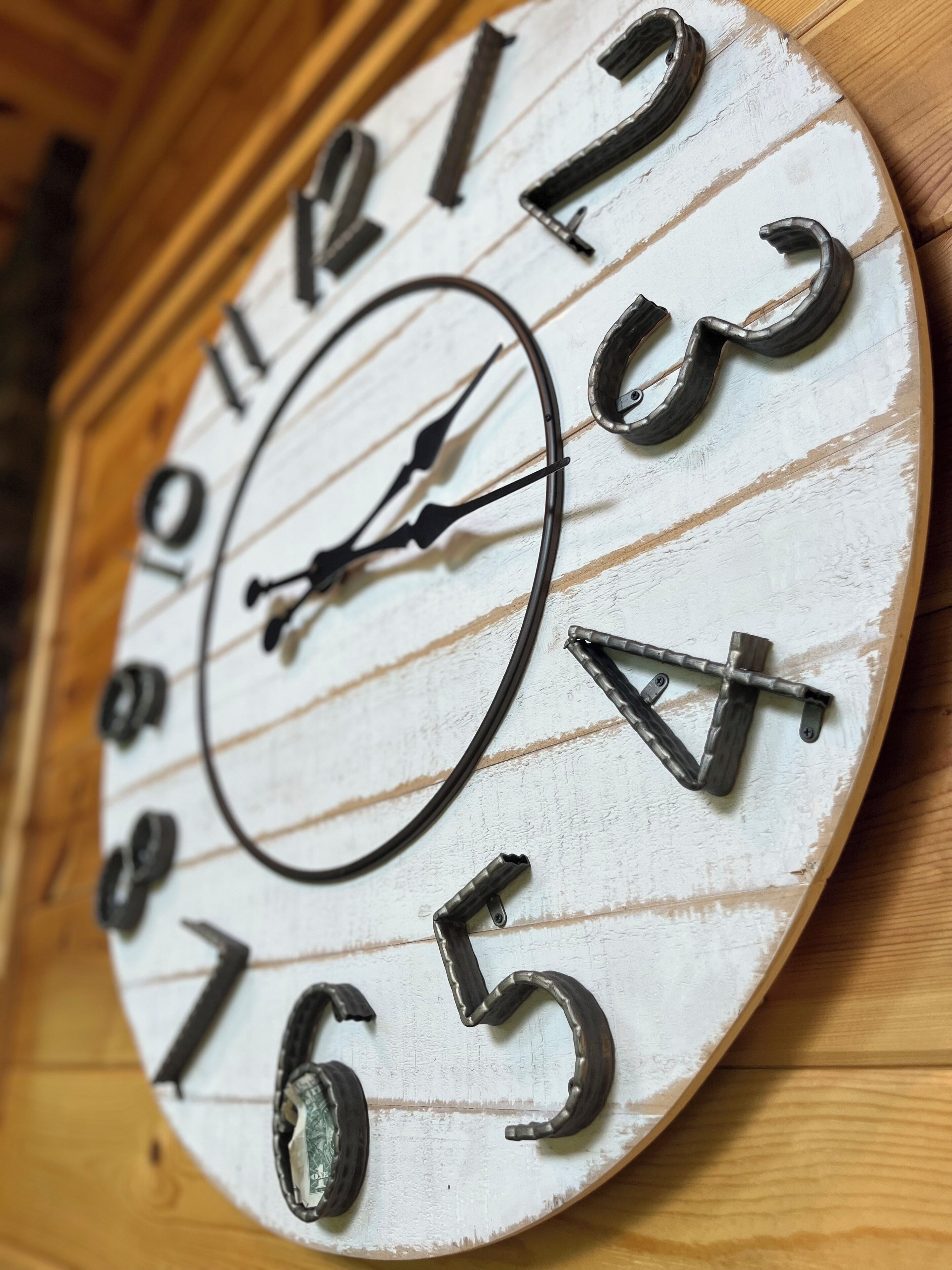 A rustic wall clock with a wooden frame and a white face with black numbers and hands.