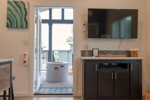 Ett modernt kök med en inbyggd ugn, en platt-TV som är monterad ovanför bänkskivan och en dörr som leder ut till ett utomhusområde.