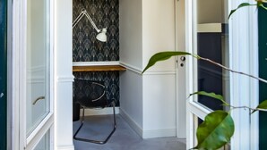Une petite pièce étroite, avec un bureau, une chaise et une lampe de bureau fixée au mur.