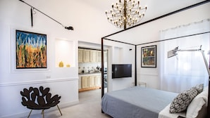 Une chambre à coucher moderne avec un lit à baldaquin, une chaise originale et des œuvres d’art accrochées aux murs.