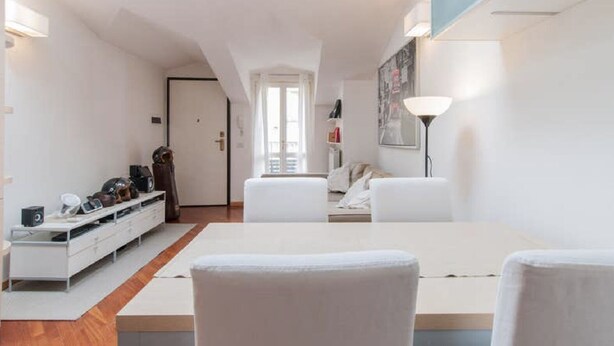 Una sala de estar moderna con un sofá blanco, una mesa de comedor y un zapatero.