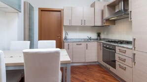 Una cocina compacta con armarios de madera clara, estufa integrada y un lavamanos.