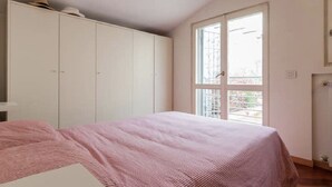 Un dormitorio con cama, armario y ventana con vistas.
